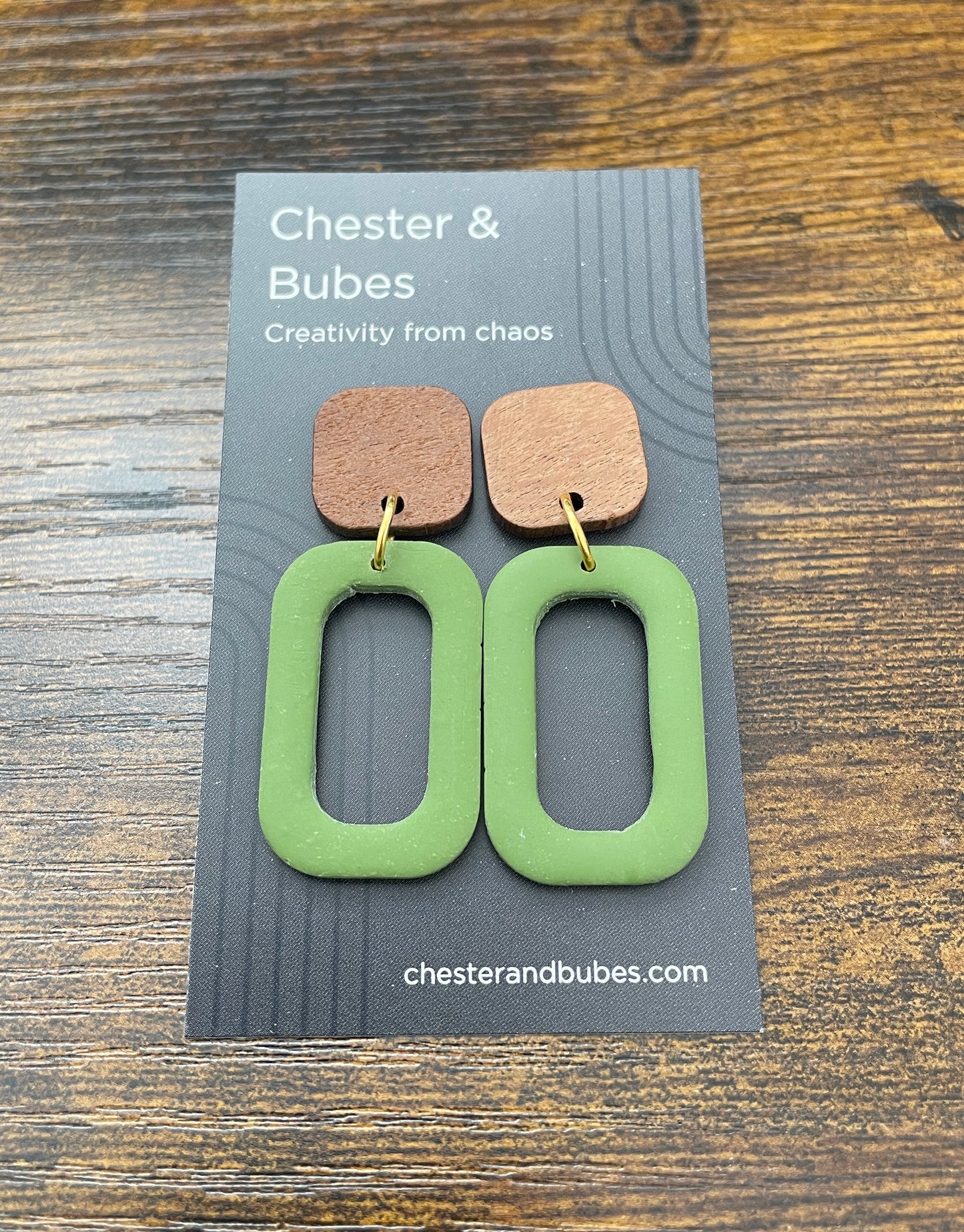 Green earrings on a Chester & Bubes branded card with a wooden background