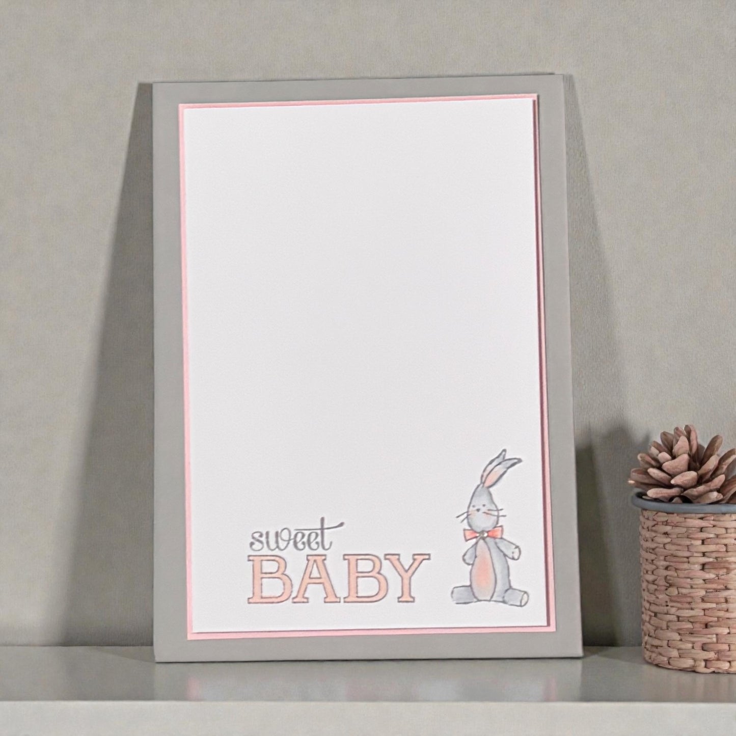 New baby card with a bunny illustration on a gray surface.