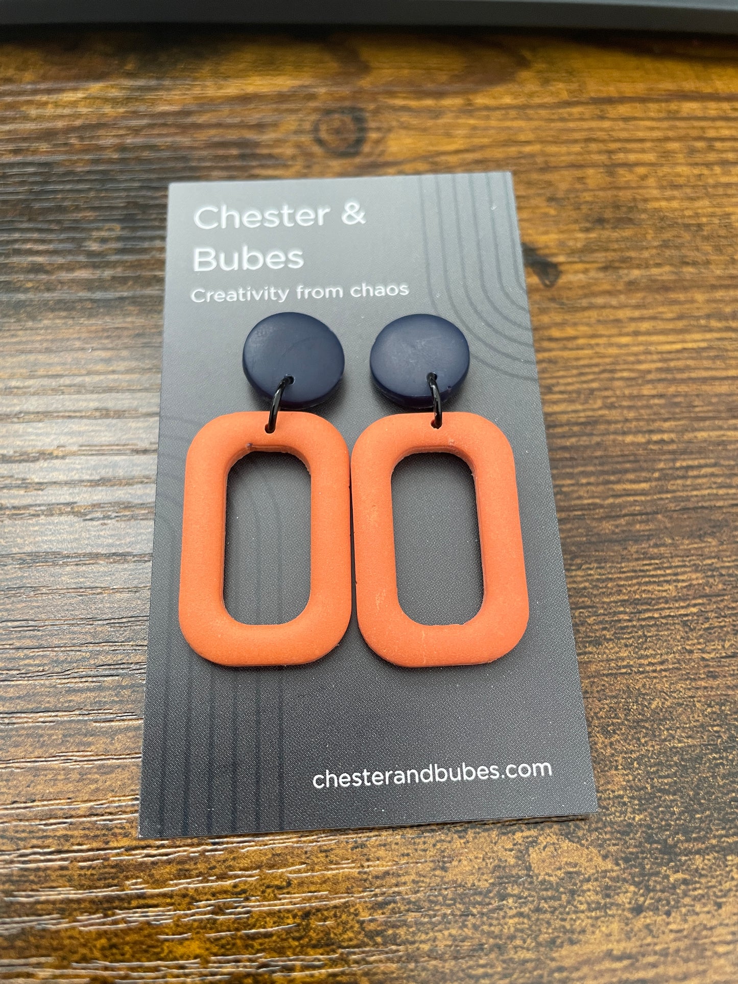 Pair of orange squoval earrings with a dark blue round topper.