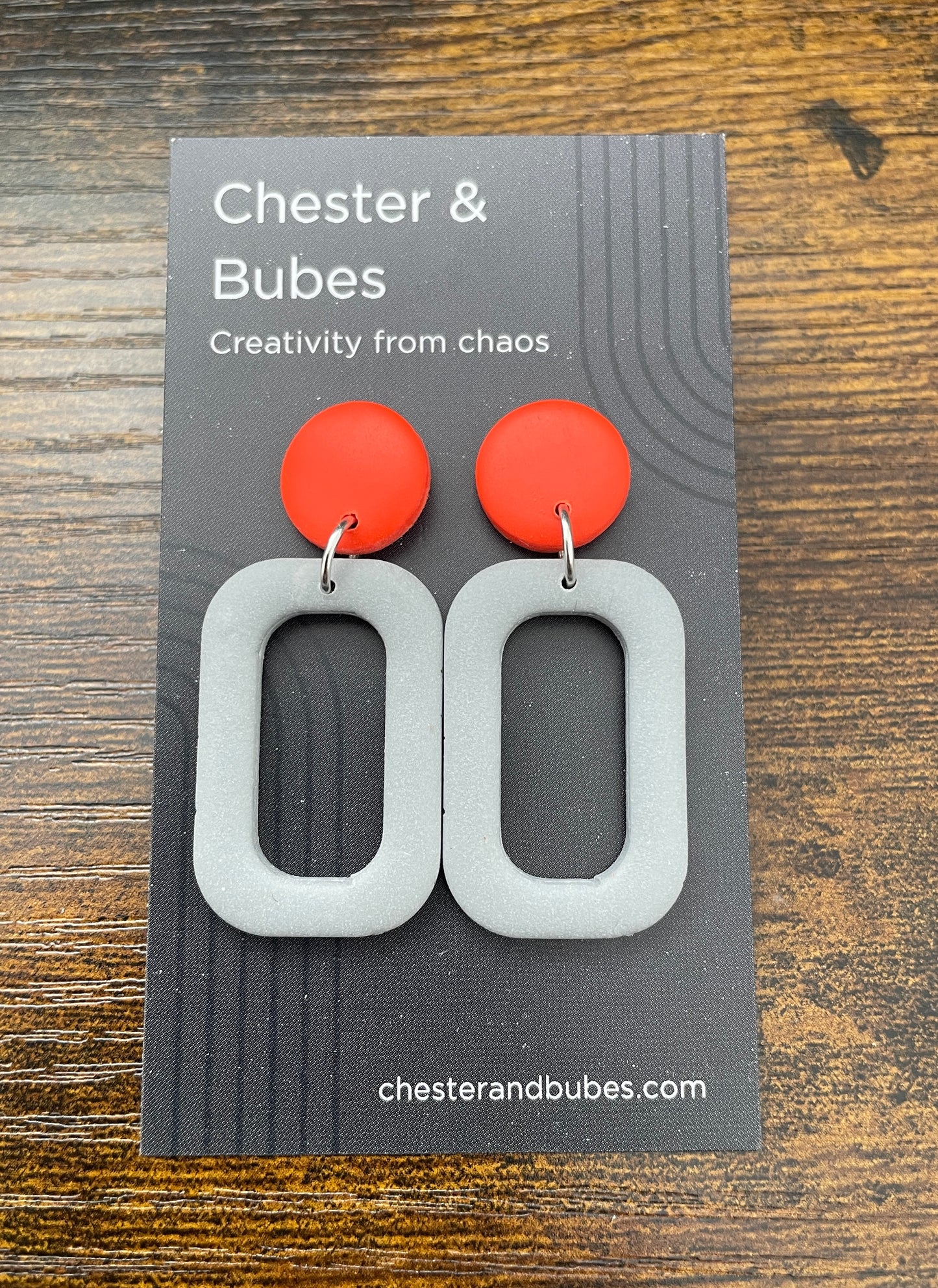 Earrings with a bright orange copper with a grey squoval cutout shape.