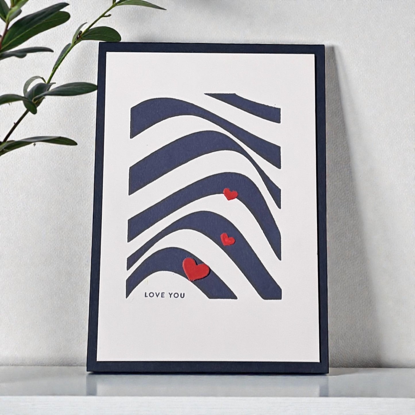 Graphic card with swirly navy blue lines and a 'love you' sentiment, accented with three little red heart embellishments