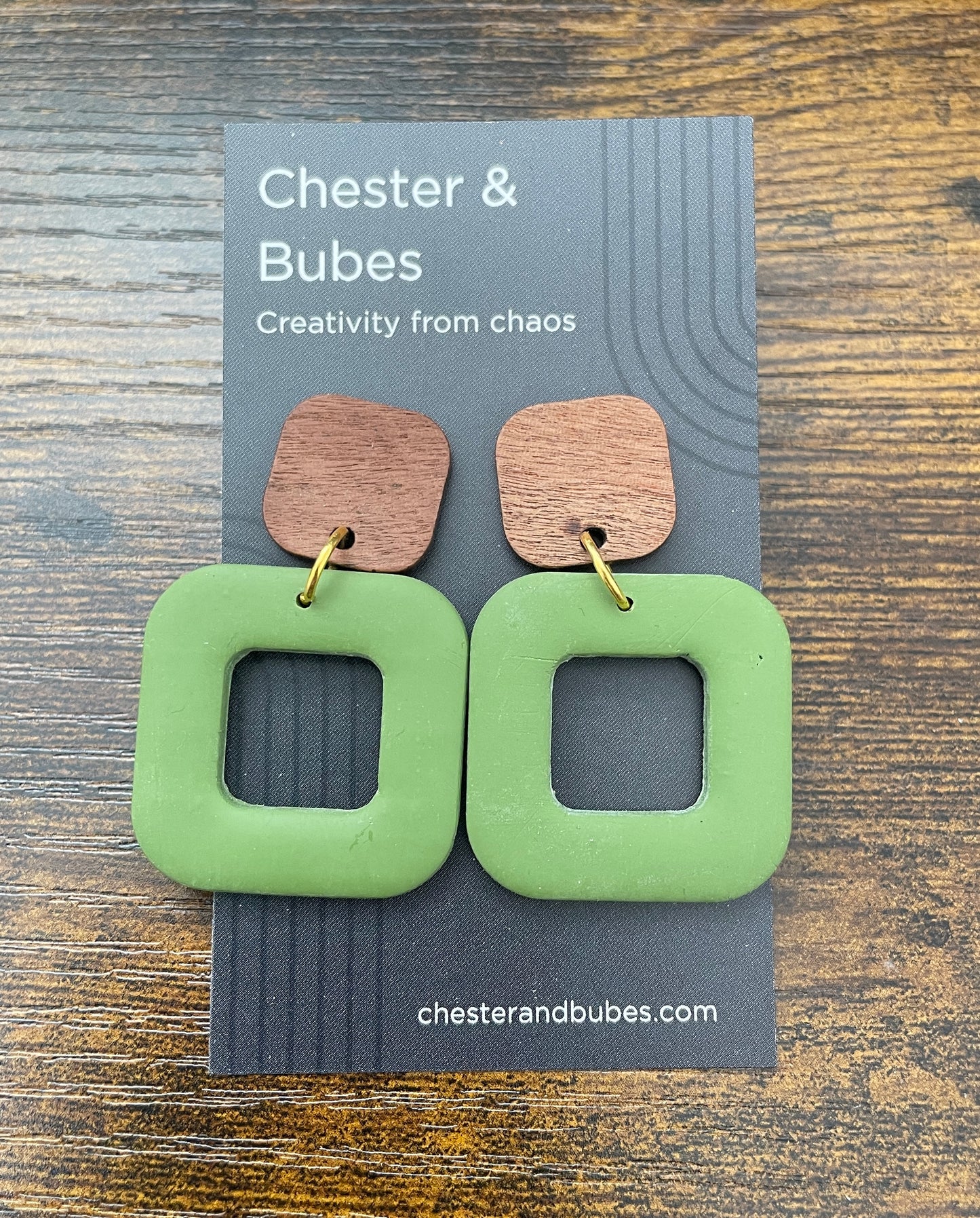 Green square earrings on a Chester & Bubes branded card with a wooden background