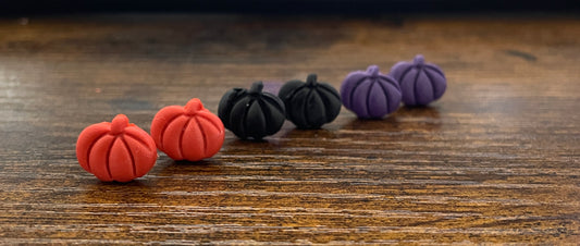 Colourful pumpkin-shaped earrings on a wooden surface