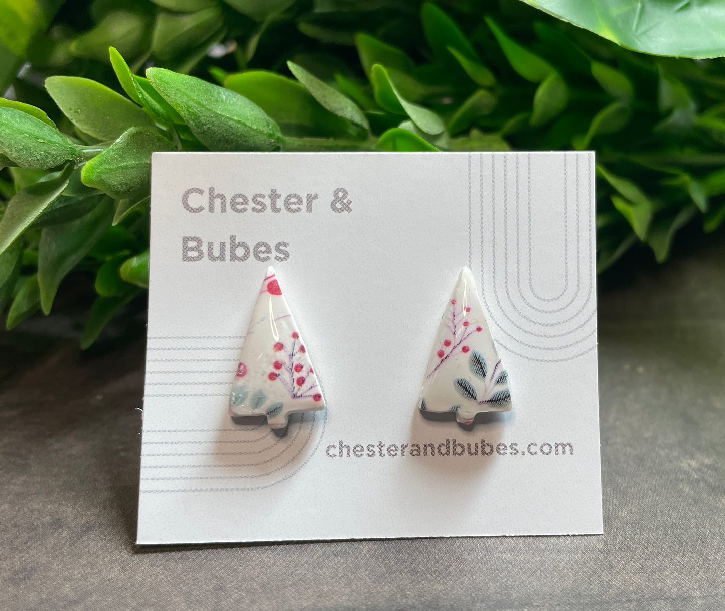 Festive pattern Christmas tree earrings on a 'Chester & Bubes' branded card with green leaves in the background