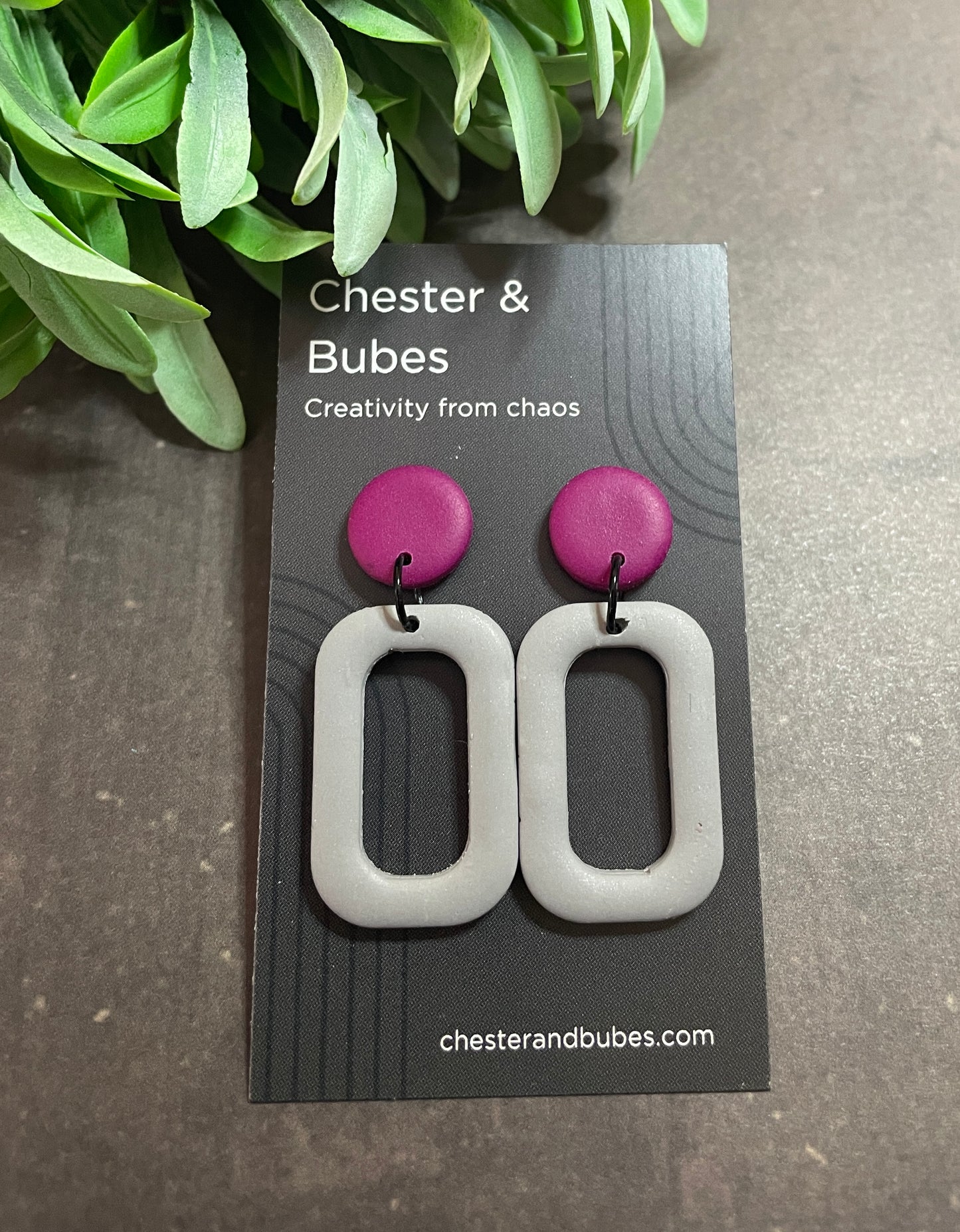 Pair of earrings with pink and gray design on a 'Chester & Bubes' branded card.