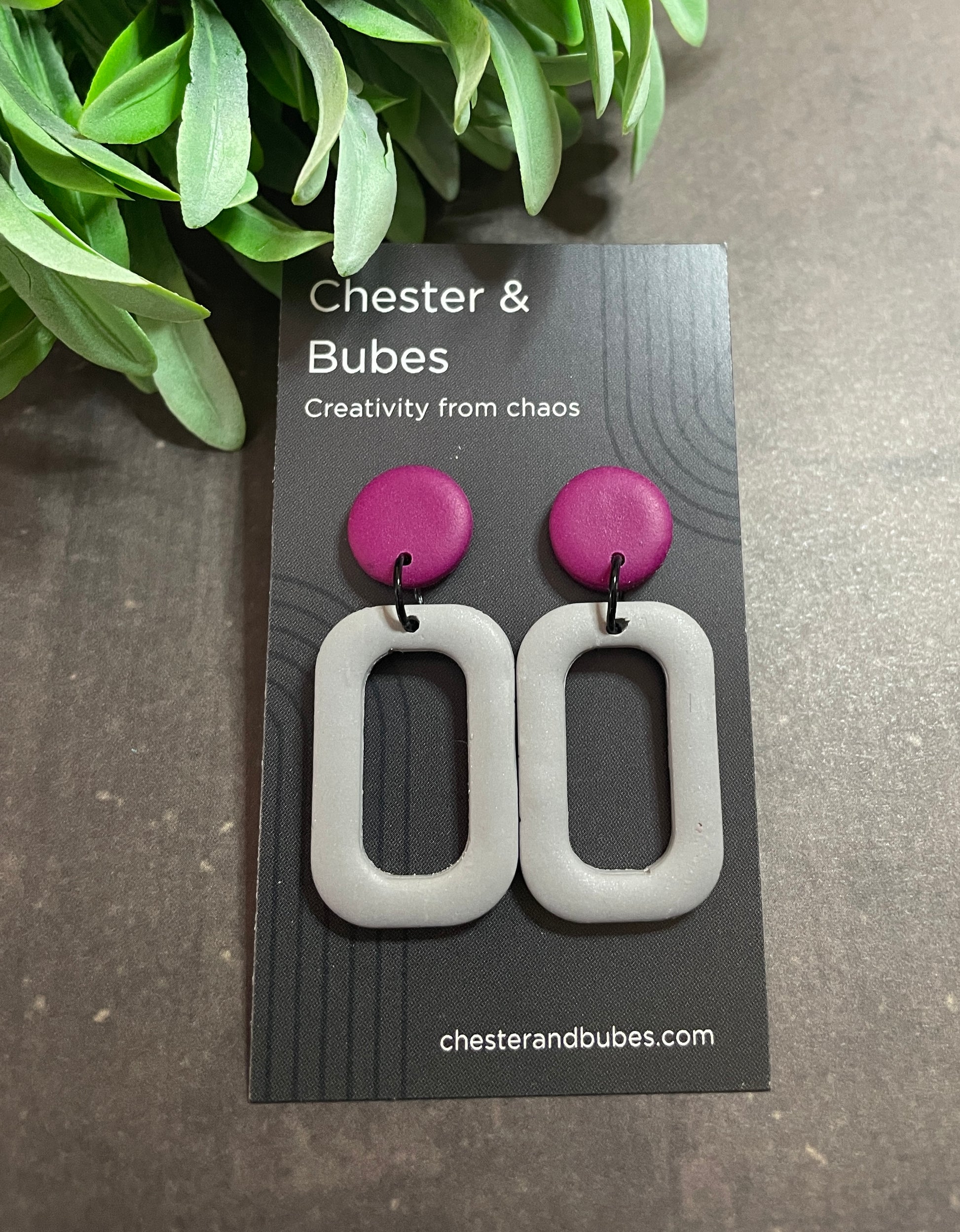Pair of earrings with pink and gray design on a 'Chester & Bubes' branded card.