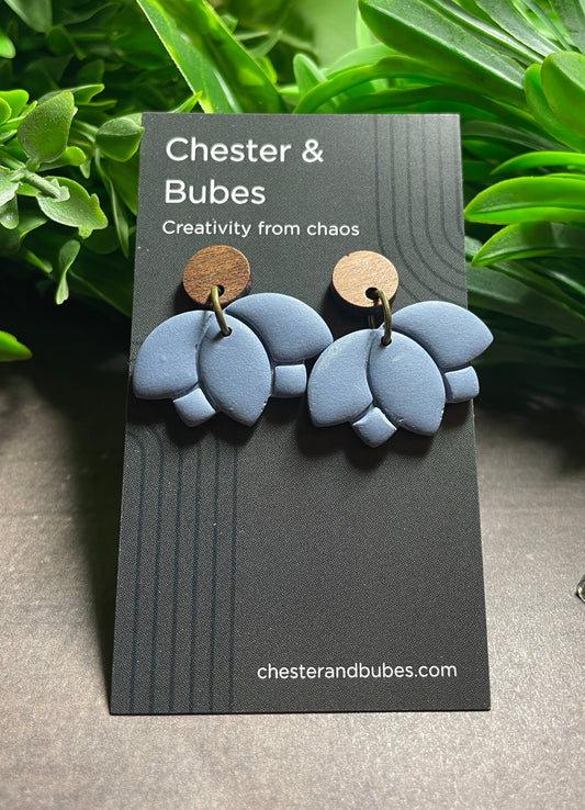 Blue earrings on a 'Chester & Bubes' branded card with green leaves in the background