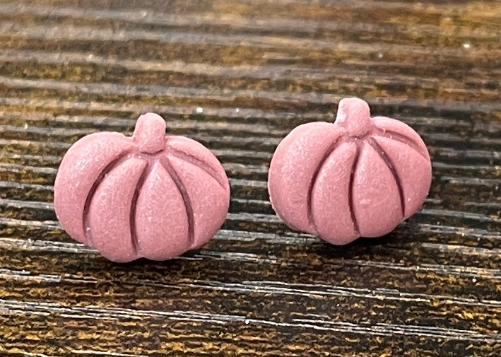 Dusky pink pumpkin-shaped earrings on a wooden surface