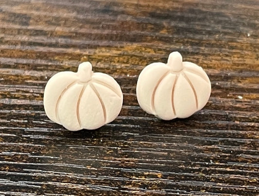 Pair of rich vanilla coloured pumpkin-shaped earrings on a wooden surface