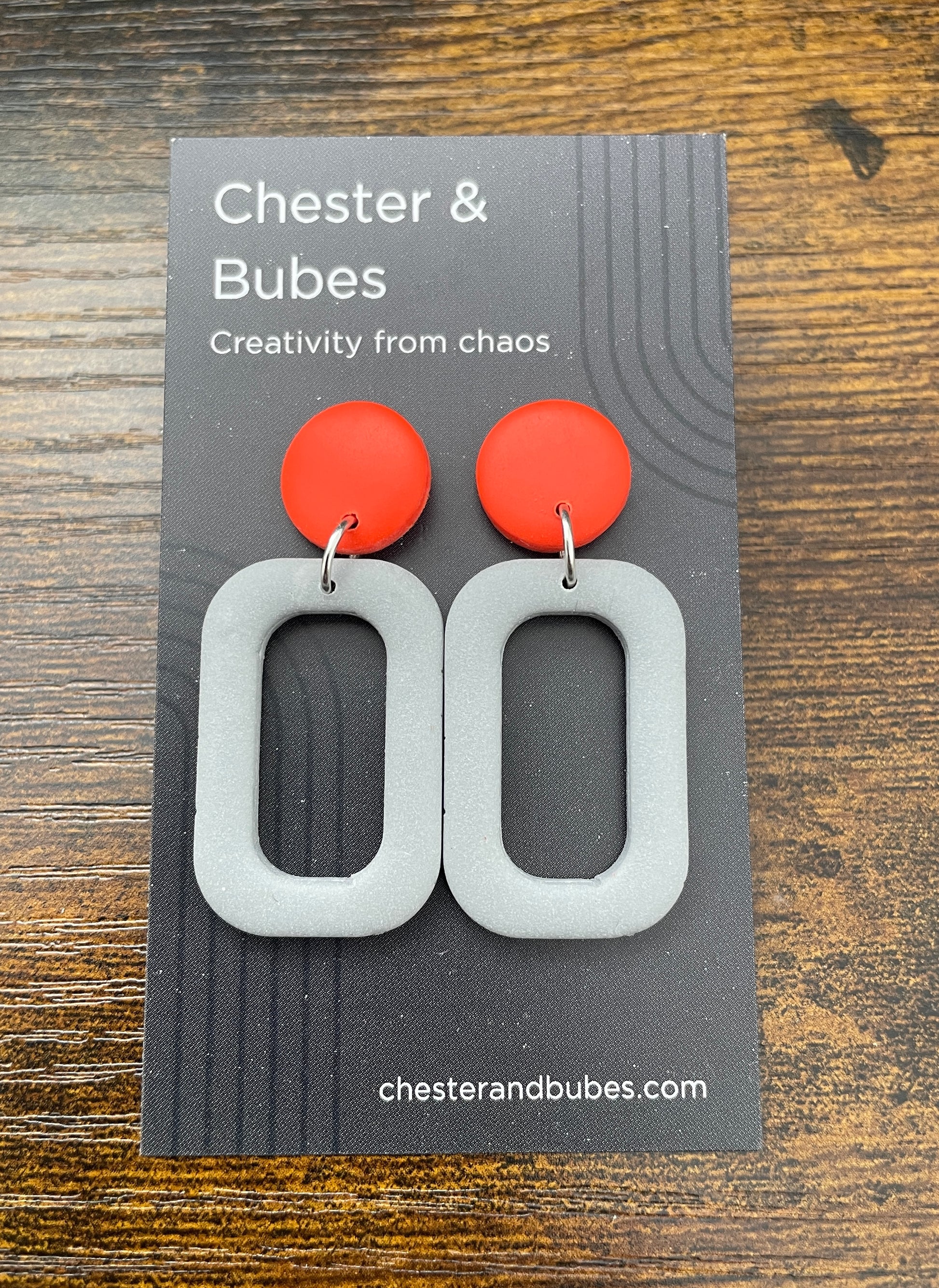 Earrings with a bright orange copper with a grey squoval cutout shape. 