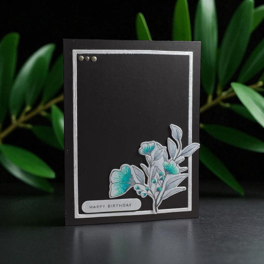 Black birthday card with floral design and 'Happy Birthday' text, against a dark background with green leaves.