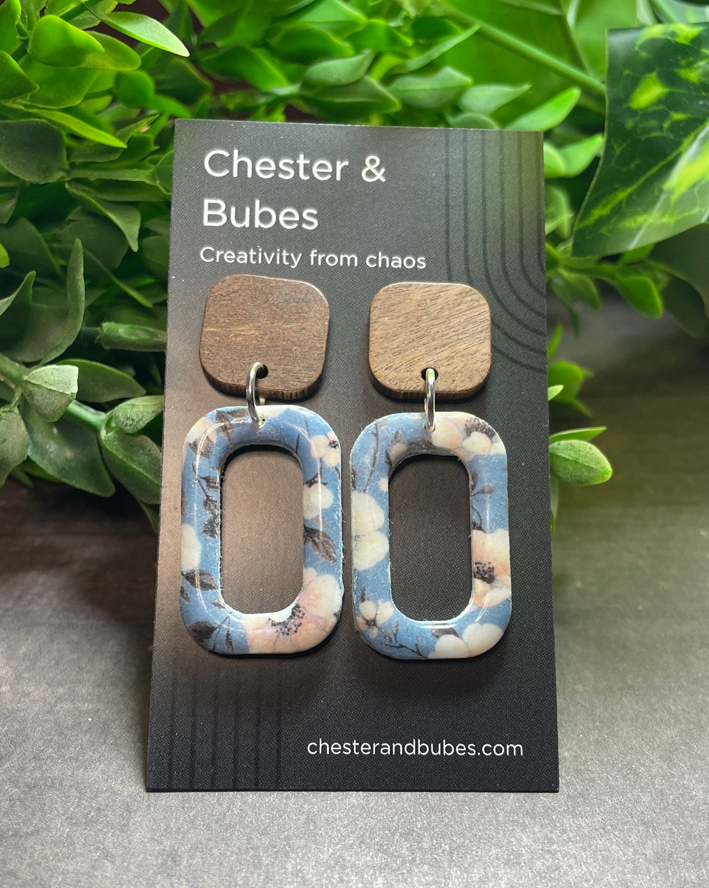 Pair of earrings on a 'Chester & Bubes' branded card with green foliage in the background