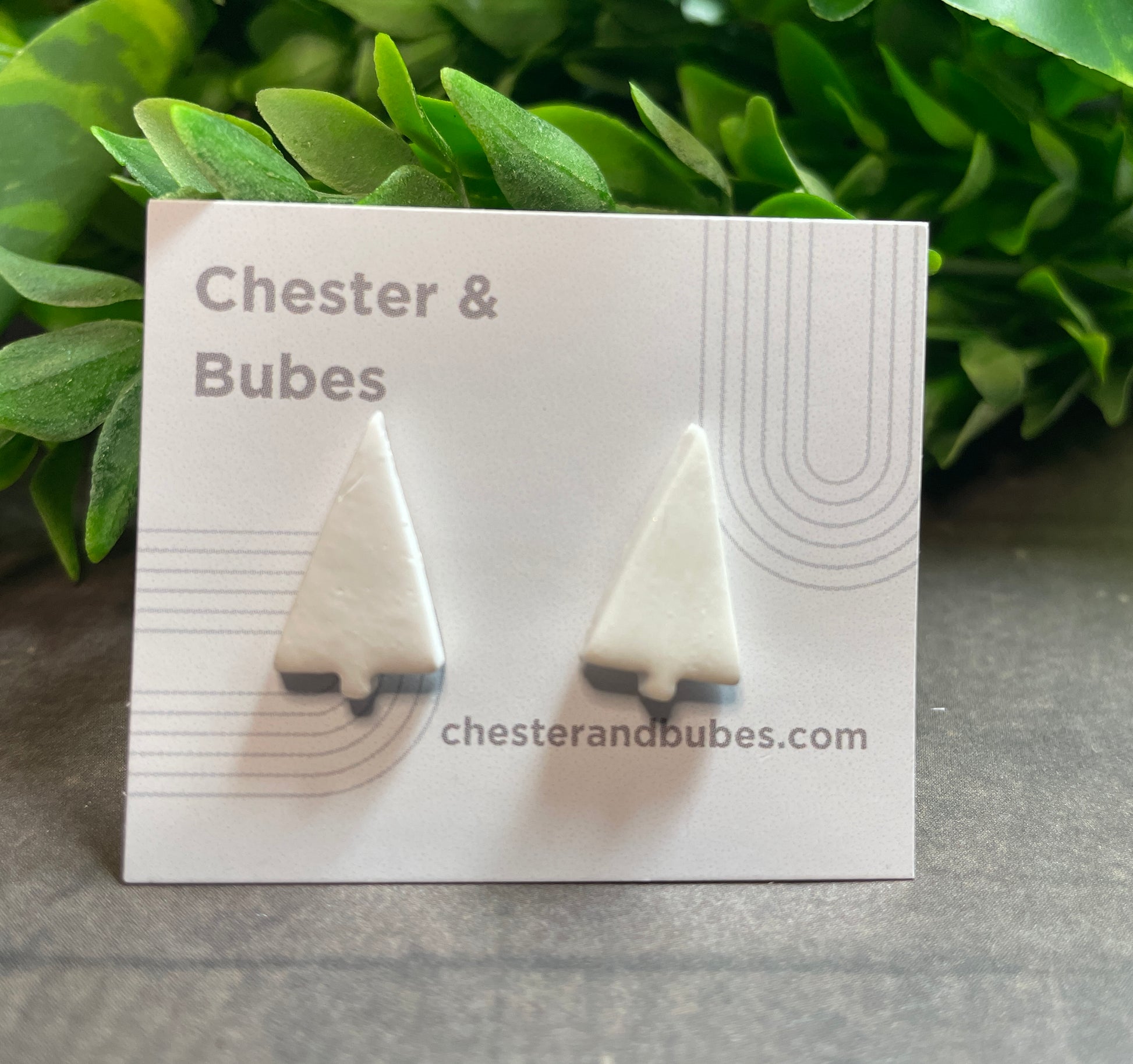 White Christmas tree earrings on a 'Chester & Bubes' branded card with green leaves in the background