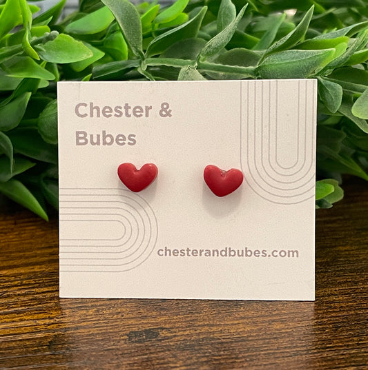 Cranberry red heart-shaped earrings on a 'Chester & Bubes' branded card with green leaves in the background.