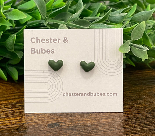 Dark green heart-shaped earrings on a 'Chester & Bubes' branded card with green leaves in the background.